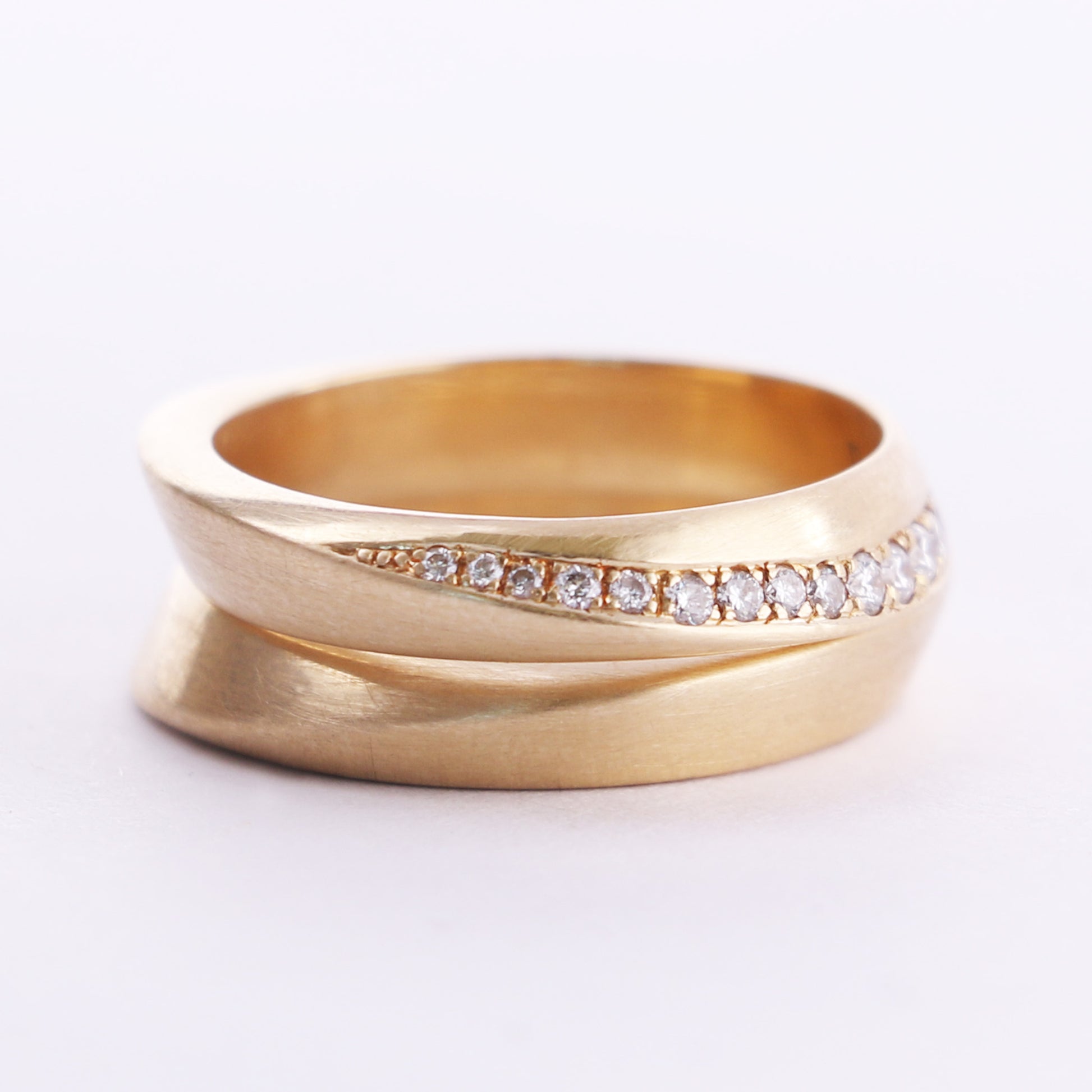 two gold rings stacked together. top ring is set with diamonds