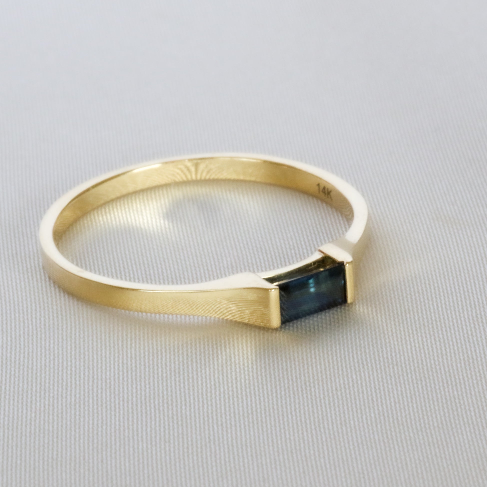 blue sapphire baguette ring in off side on off white cloth