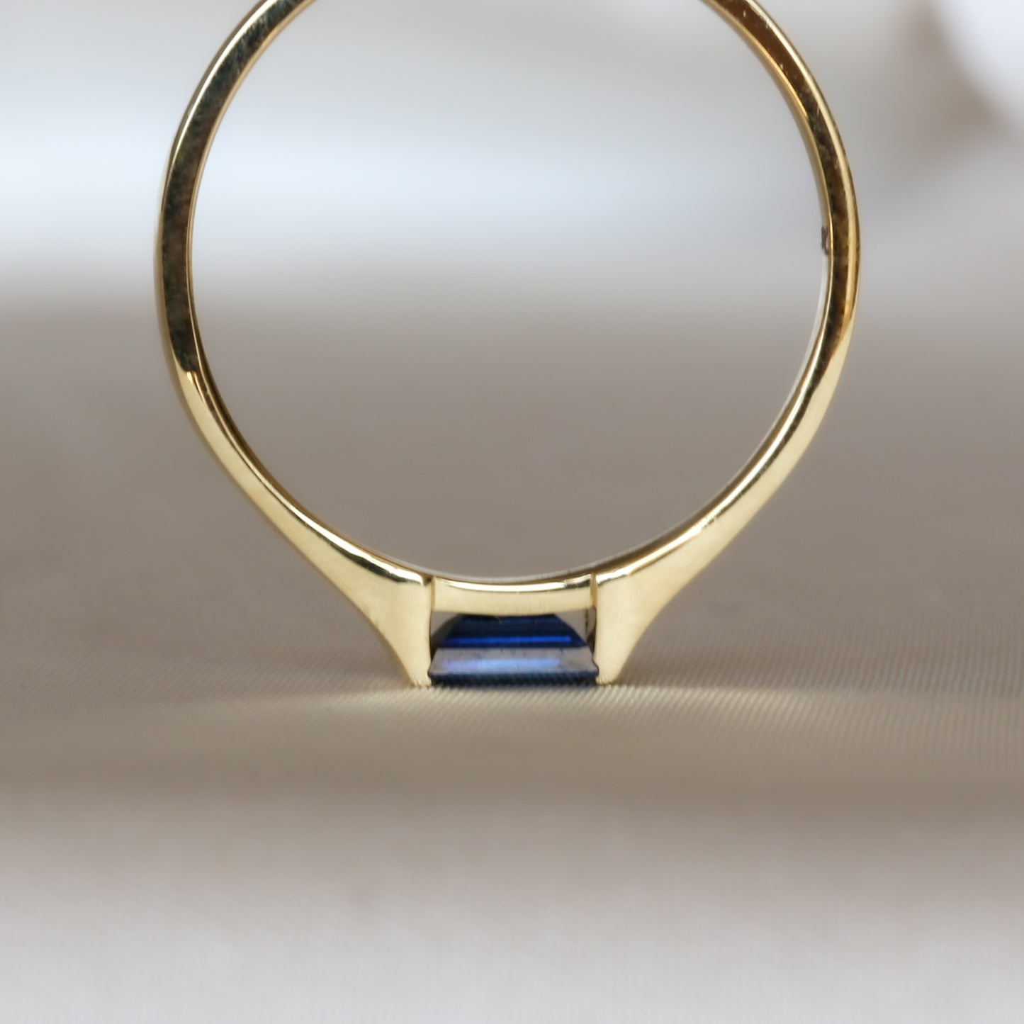 blue sapphire ring standing up side down on stone table