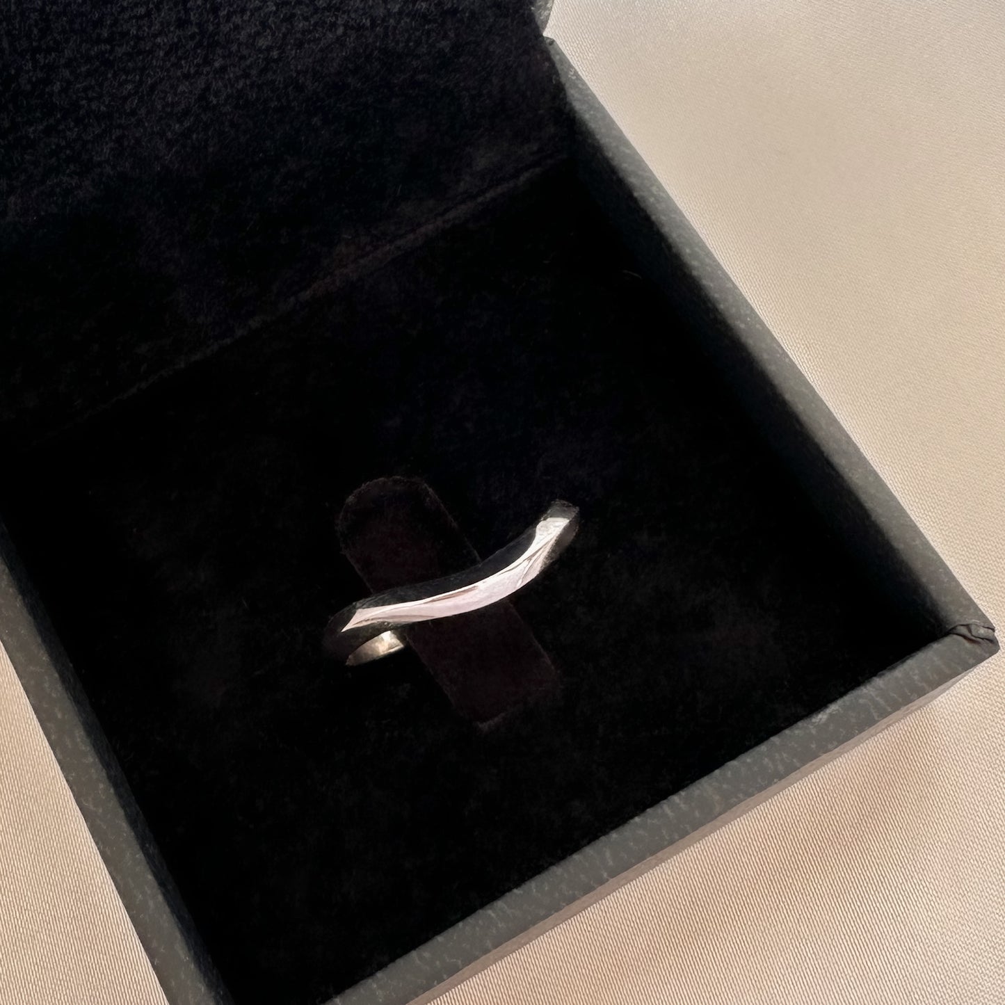 A 14K gold ring with a modern geometric wavy design, sitting in black velvet box