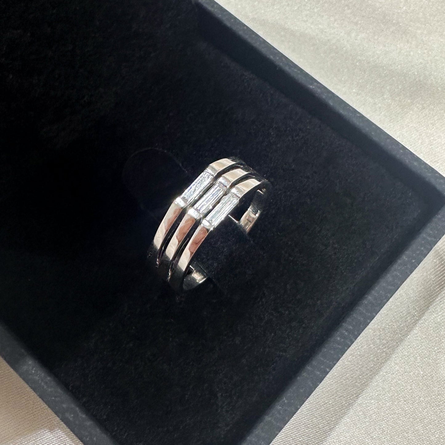 A minimalist ring design with a stack of needle baguette cut sapphires, set in a 14K gold band, presented on a black velvet surface.