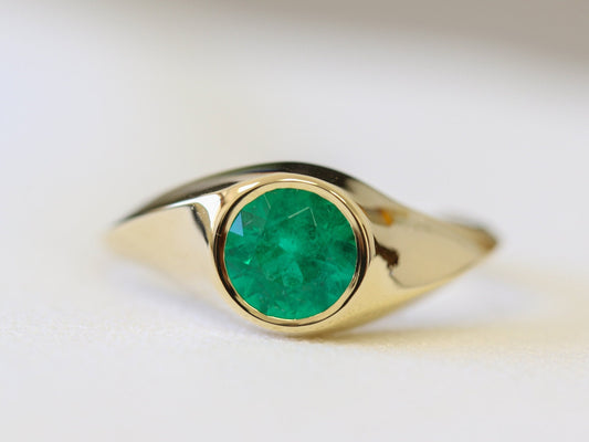 Natural emerald signet ring with a twisted yellow gold band, round stone in a bezel, front view