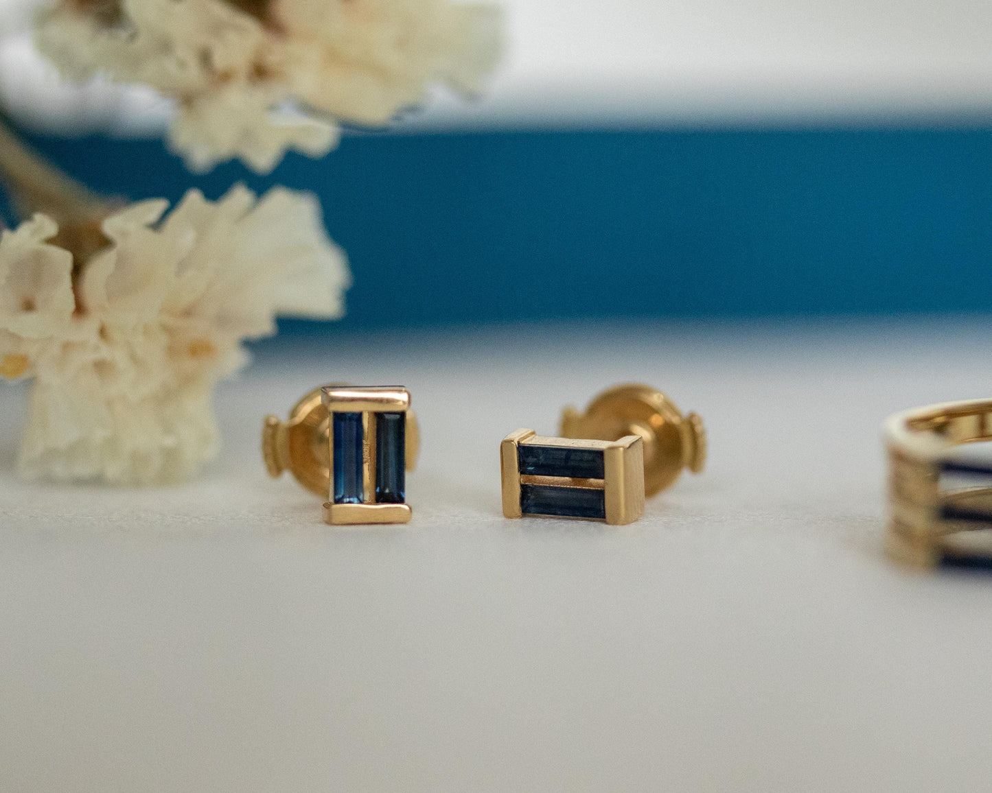 Macro view of a needle baguette blue sapphire set in a gold stud