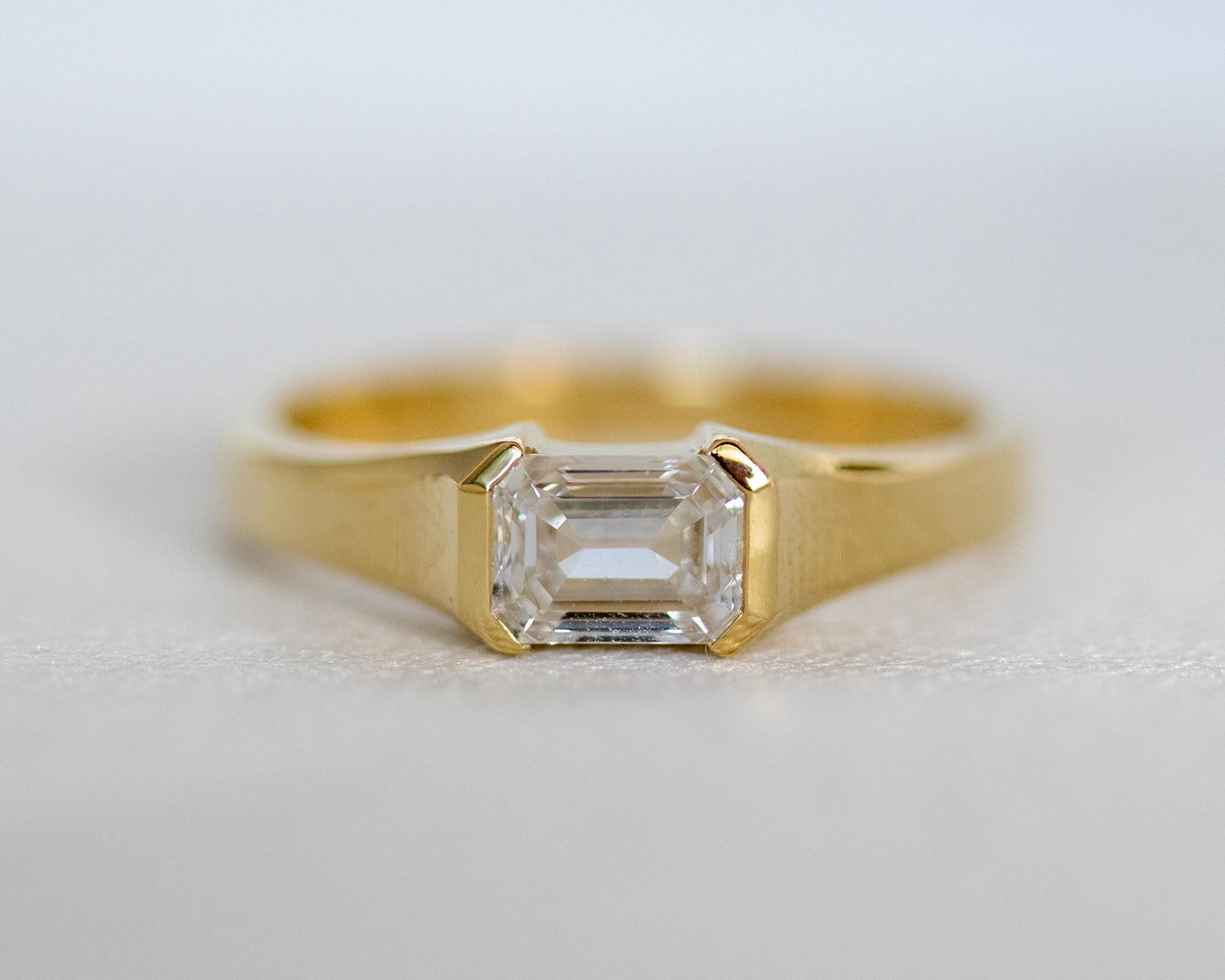 Gold ring with a diamond on a light gray background
