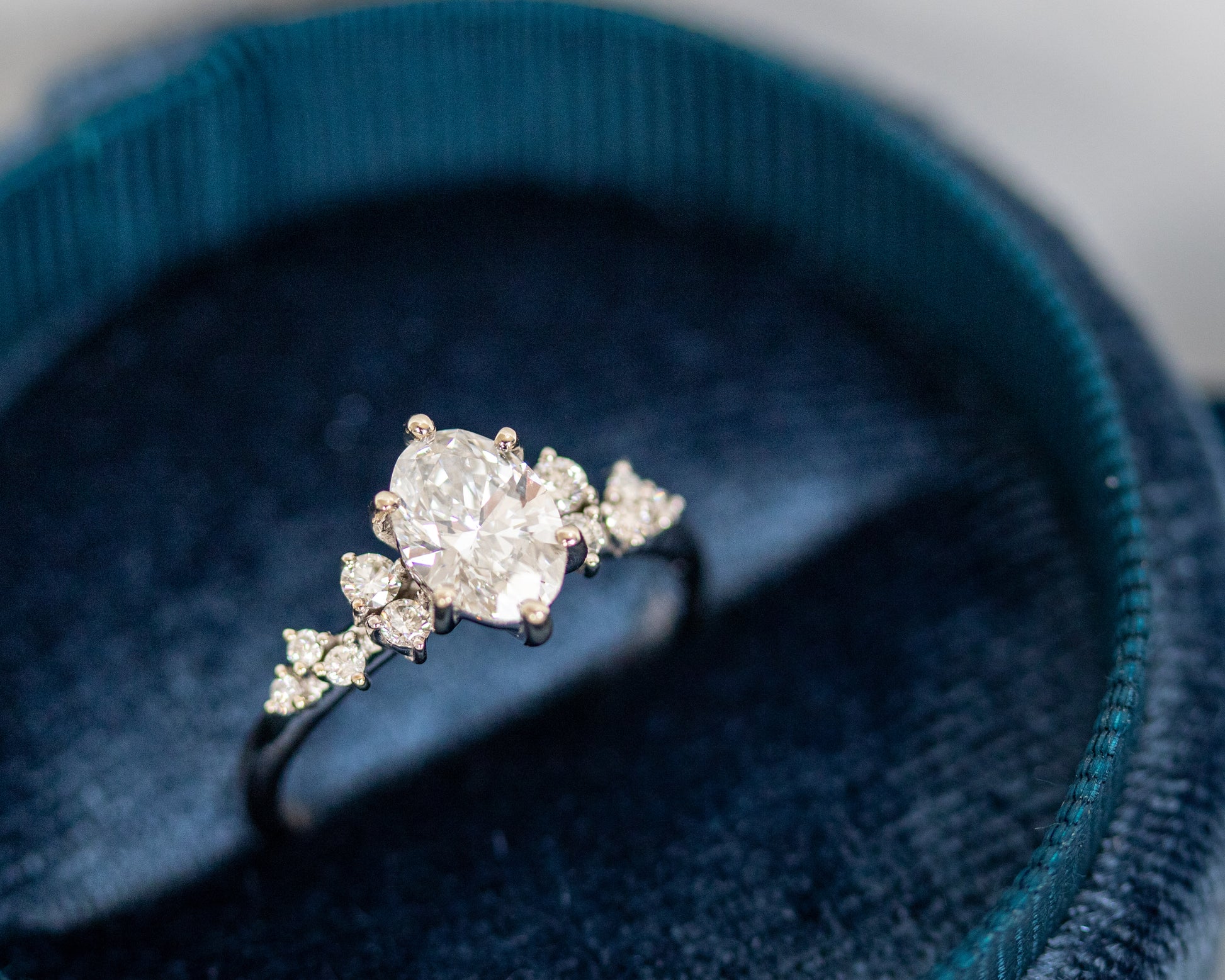 Oval diamond engagement ring displayed inside a navy blue velvet ring box