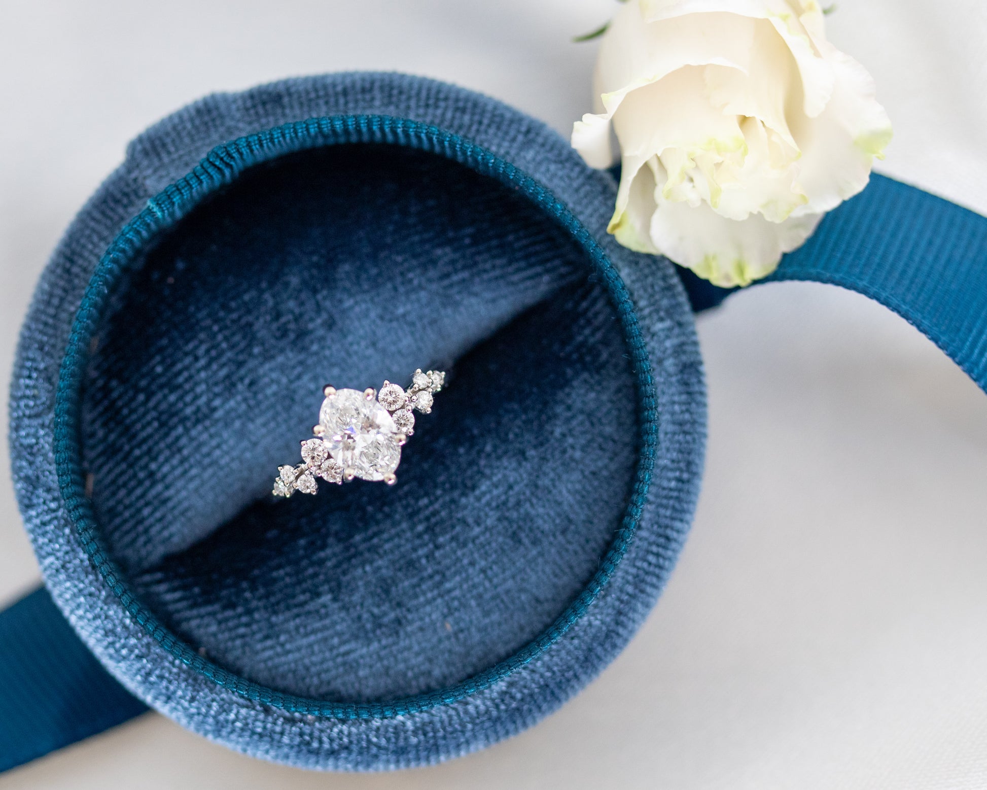 Oval diamond engagement ring displayed inside a round navy blue velvet ring box.