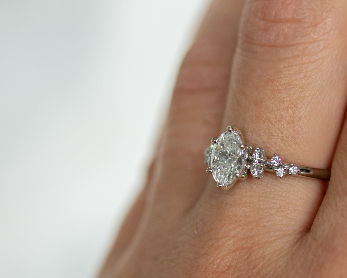 Oval diamond engagement ring worn on a hand in a lifestyle setting.