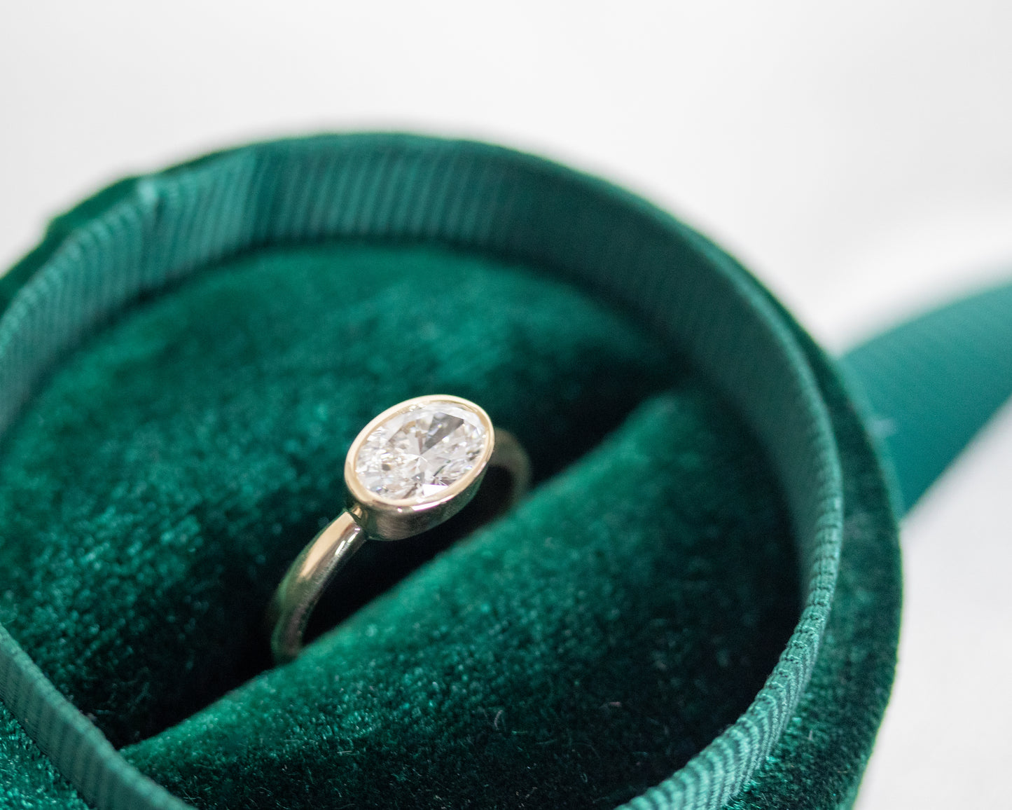 Oval diamond gold engagement ring in a green ring box — handcrafted 14K yellow gold bezel ring by Rotem Avitan Jewelry.