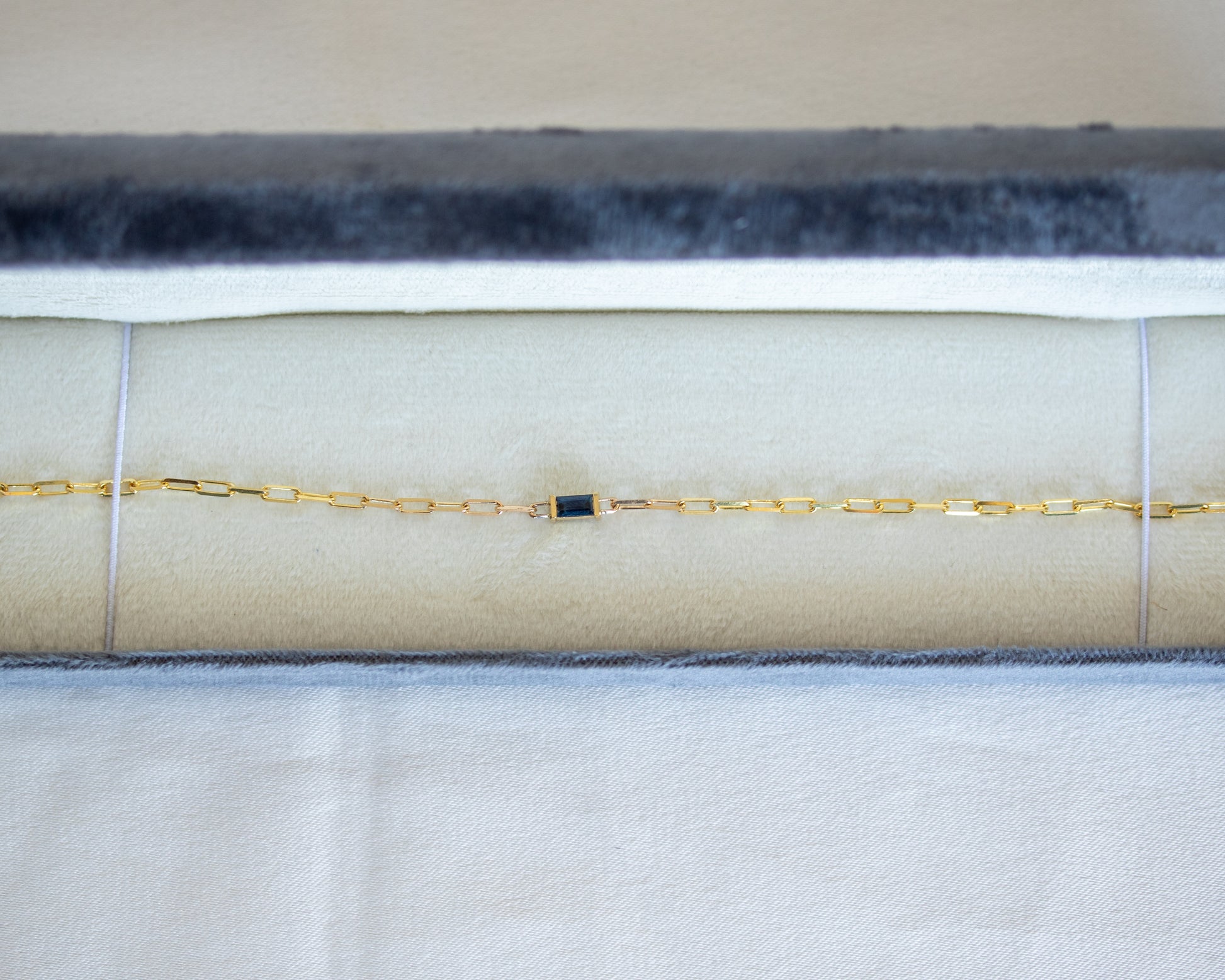 Gold bracelet with a blue baguette cut sapphire in white gray jewelry case 