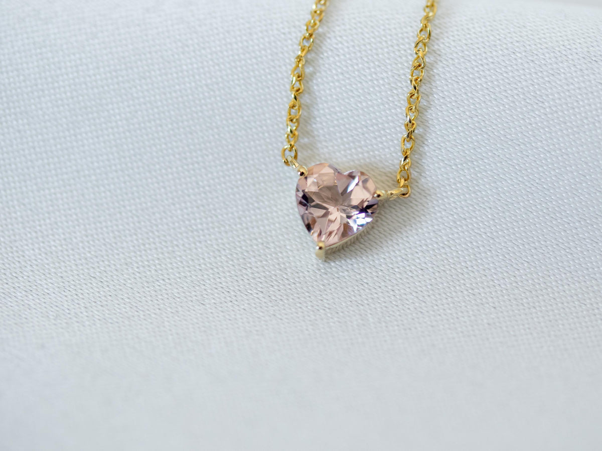 Close-up of a peach-pink heart shape morganite in a prong setting on a 14K yellow gold chain