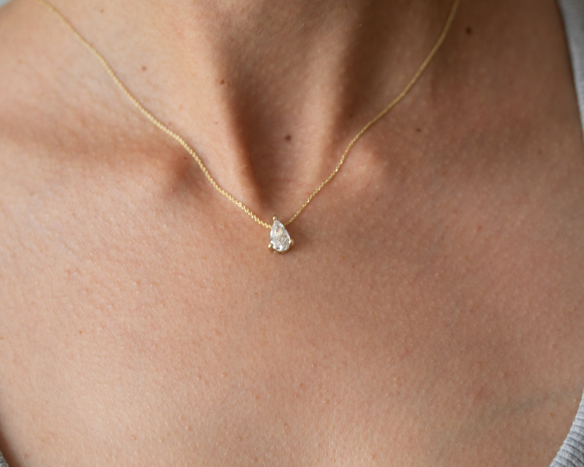 Pear diamond solitaire necklace in 14K yellow gold worn on the neck