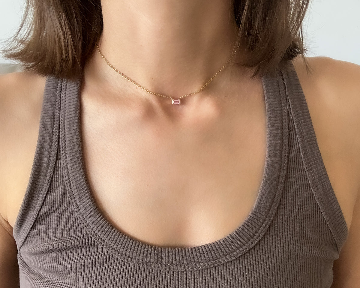 Emerald-cut pink sapphire necklace in yellow gold worn close at the base of the neck