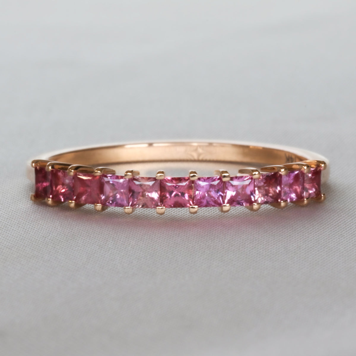 Natural pink sapphire half eternity band with princess cut stones in 14K rose gold, front view