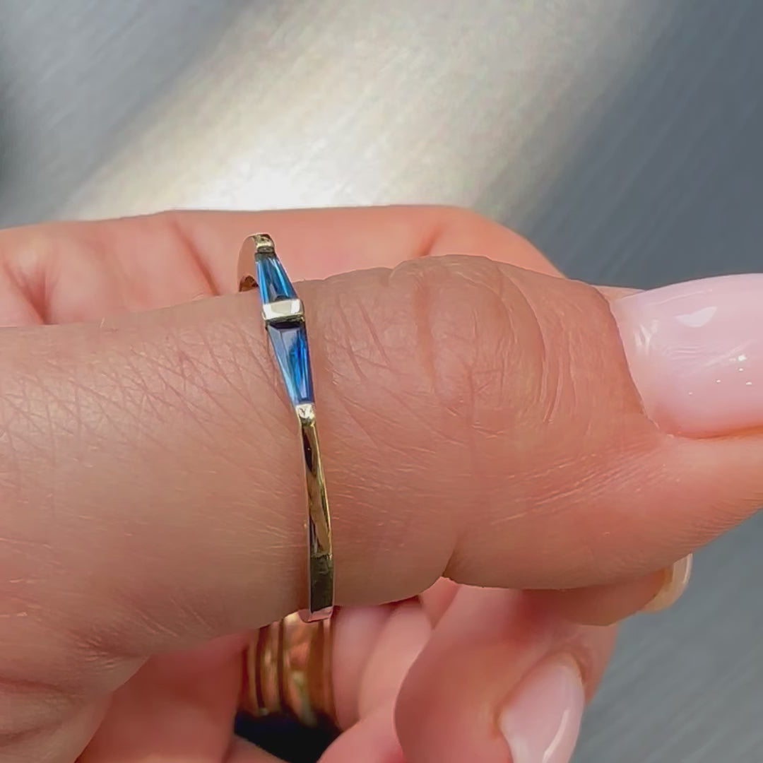 2 blue sapphires tapered baguette cut set in gold ring shown on womens hand