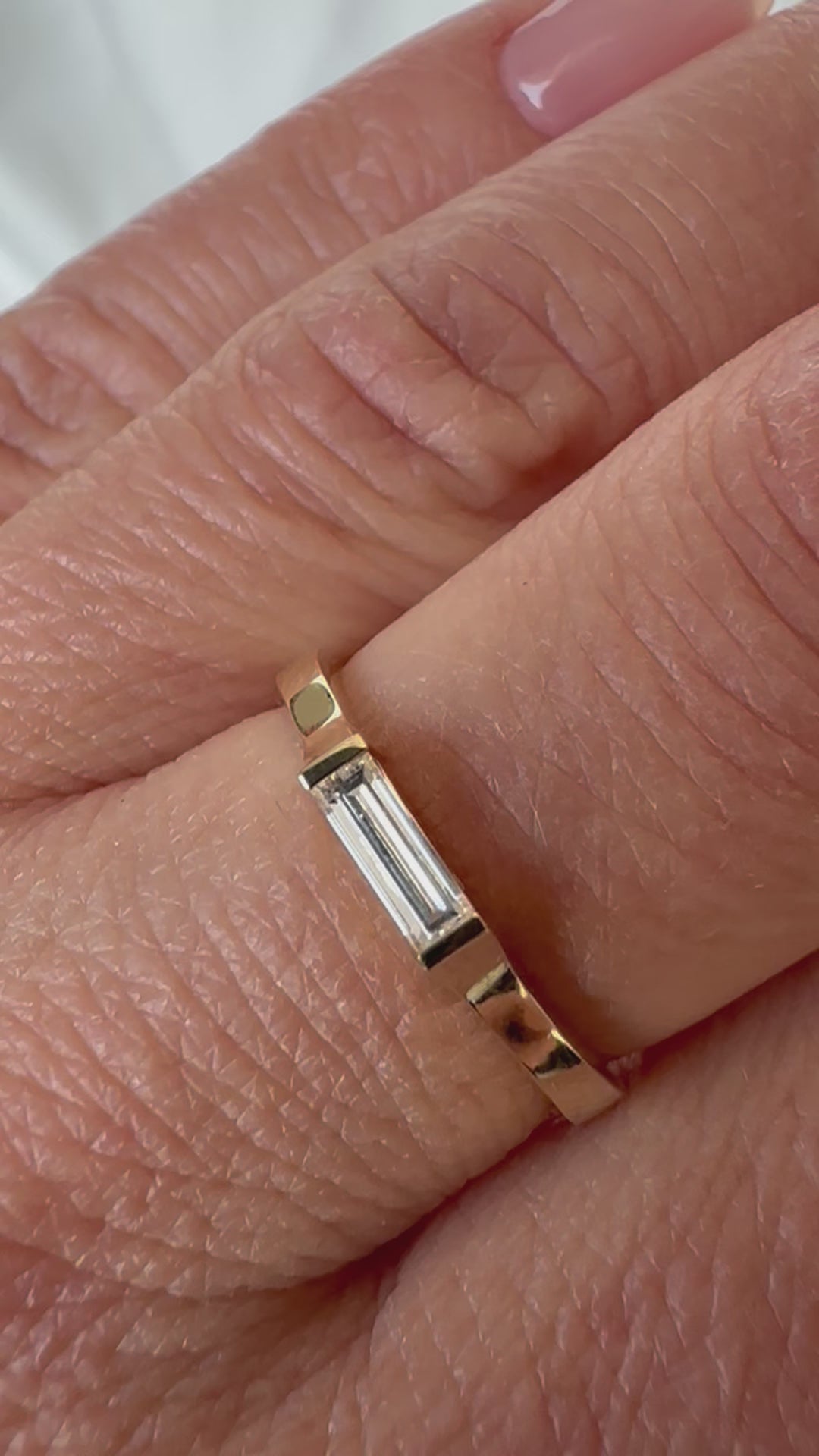 East-west baguette diamond gold ring worn on the hand