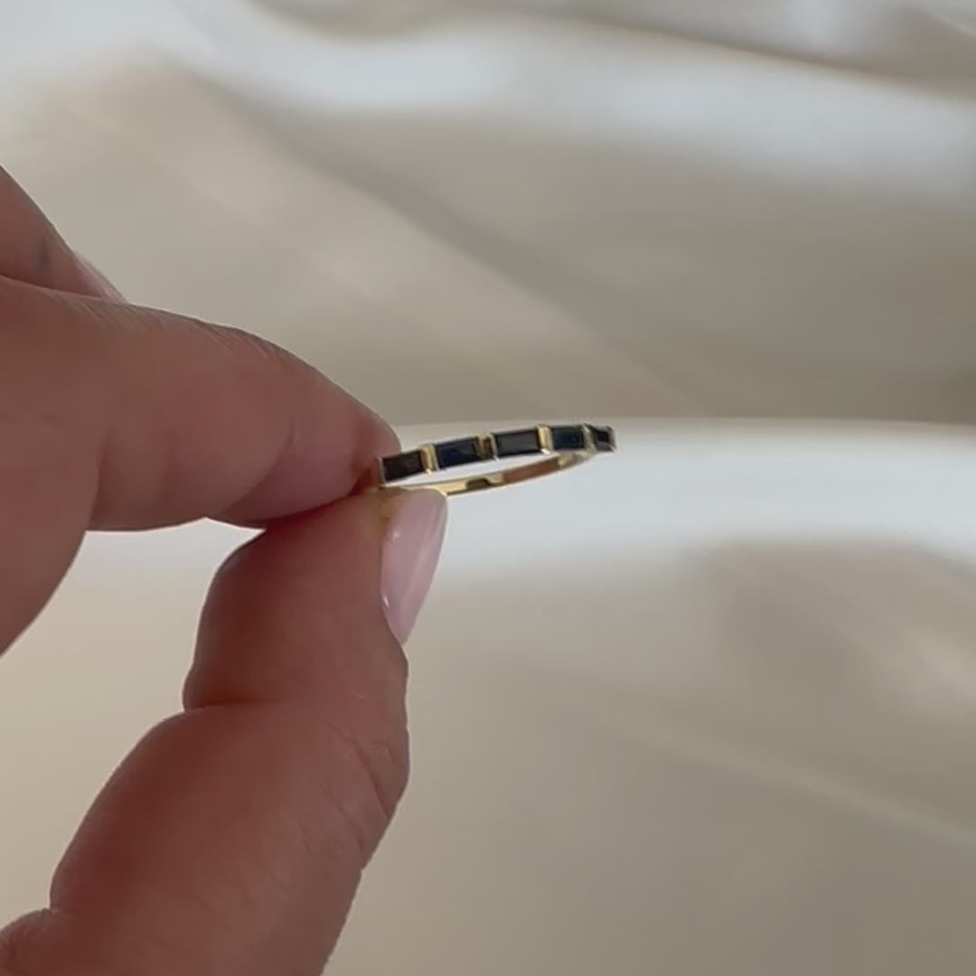 blue sapphire baguettes eternity ring displayed in women's hand