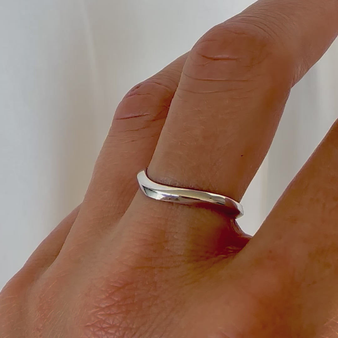 A 14K gold ring with a modern geometric wavy design, sitting on a women's hand