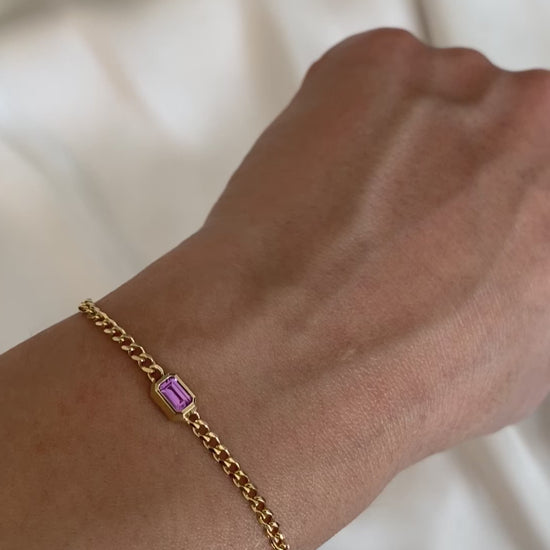 Short video of a 14K yellow gold curb chain bracelet with emerald cut pink sapphire worn on the wrist