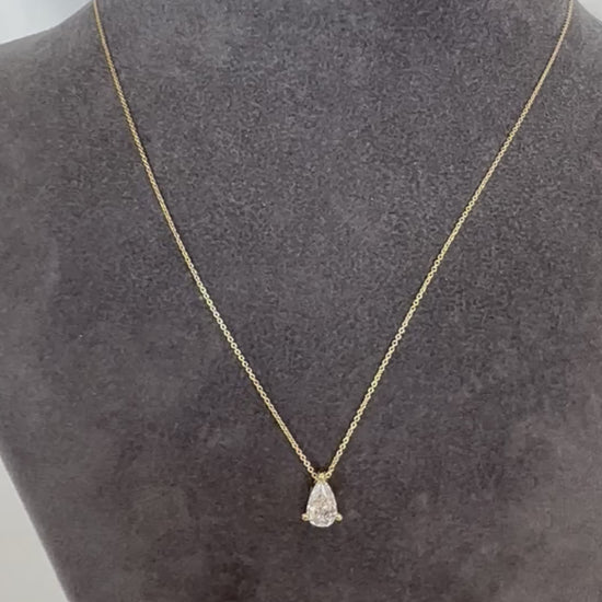Pear diamond solitaire necklace in 14K gold displayed on a gray velvet torso stand