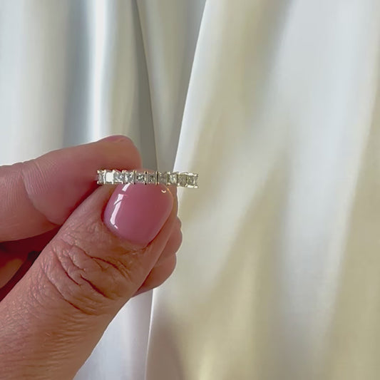 A princess cut natural diamonds eternity ring made from 14K yellow gold, displayed in persons hand