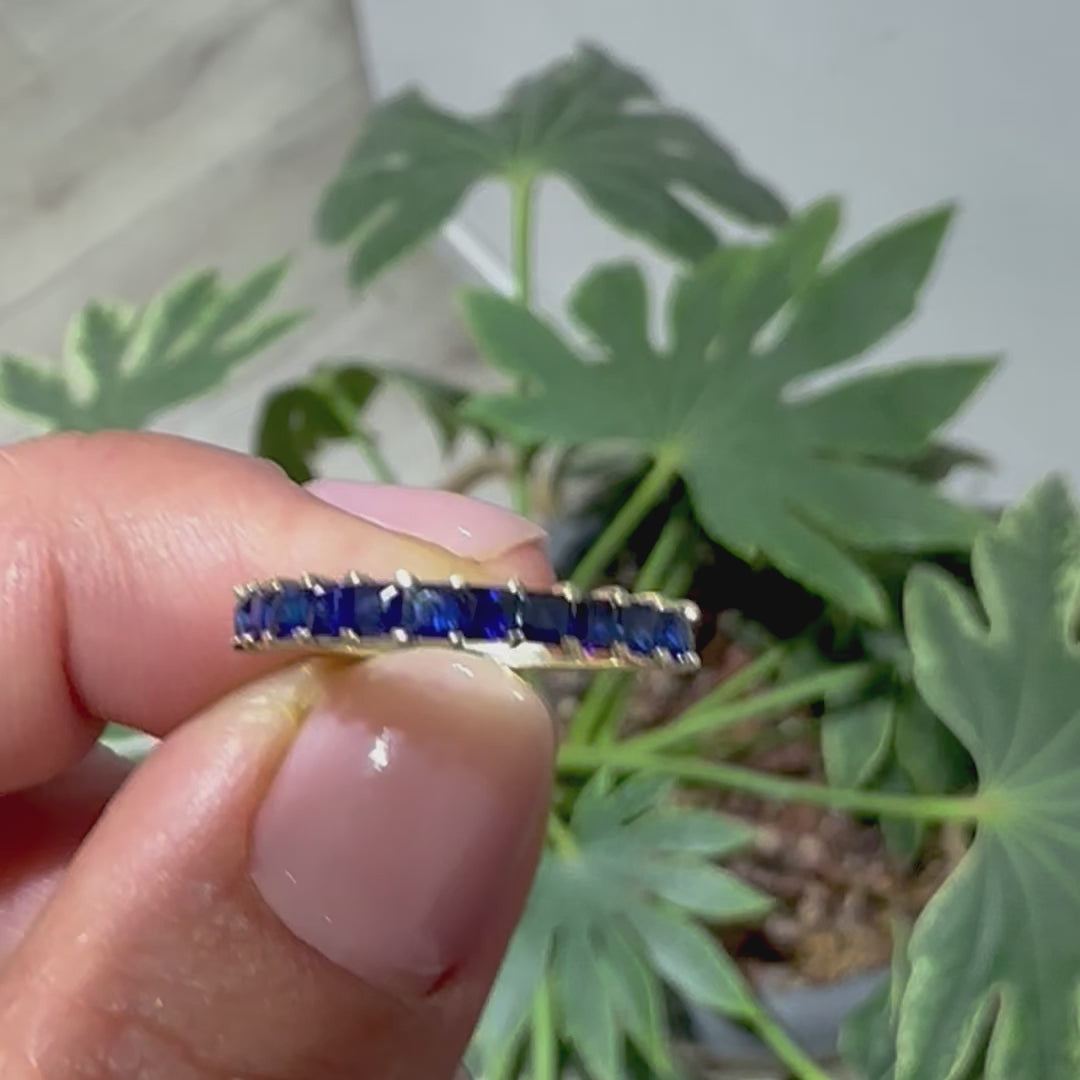  princess cut blue sapphire eternity ring displayed nn women's hand