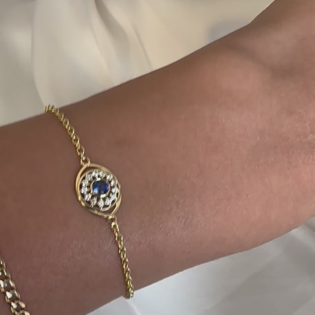 14k gold bracelet with evil eye charm with blue sapphire and natural diamonds on womens wrist 