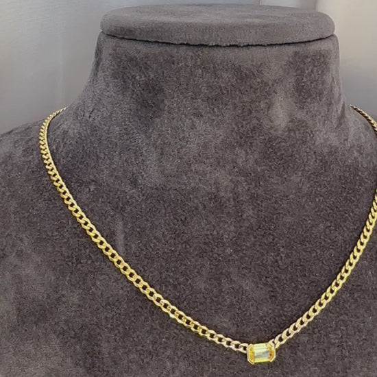 A 14K gold yellow sapphire solitaire necklace with an emerald cut natural sapphire pendant on gray texture torso