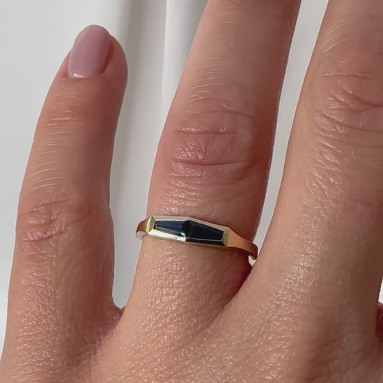 A minimalist gold ring with two blue baguette cut sapphires shown on womens hand