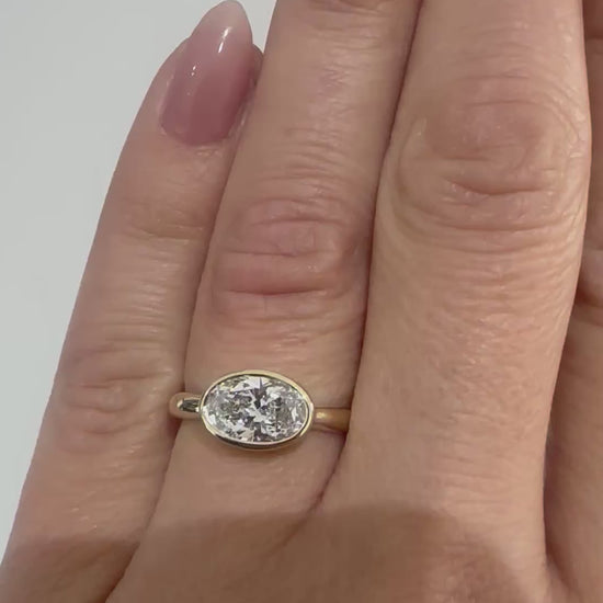 Video of oval diamond bezel-set engagement ring on hand — handcrafted 14K yellow gold ring by Rotem Avitan Jewelry.