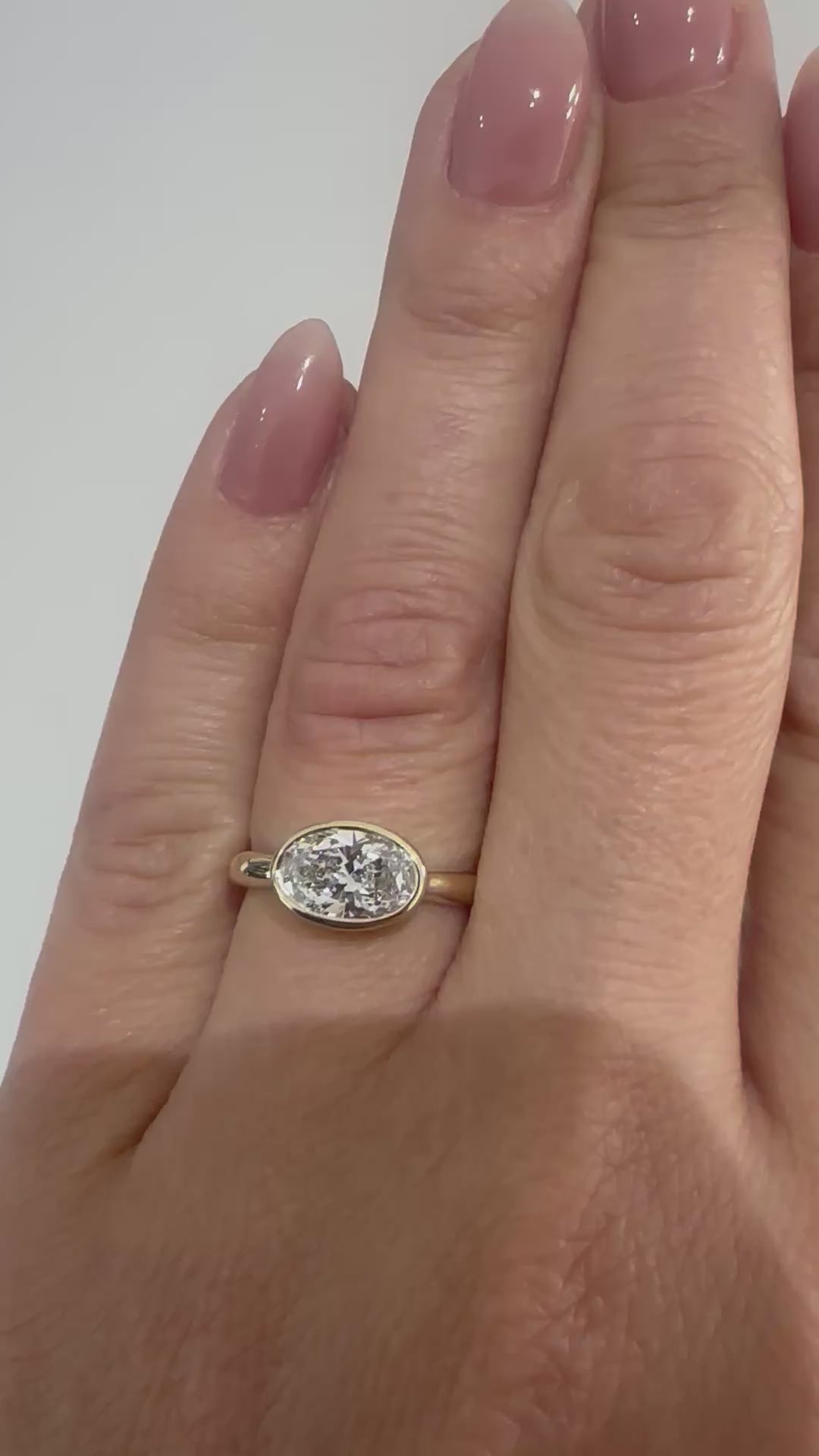 Video of oval diamond bezel-set engagement ring on hand — handcrafted 14K yellow gold ring by Rotem Avitan Jewelry.