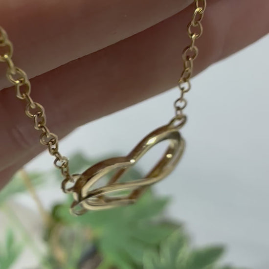 yellow gold heart and infinity symbol pendant and chain displayed in hand 