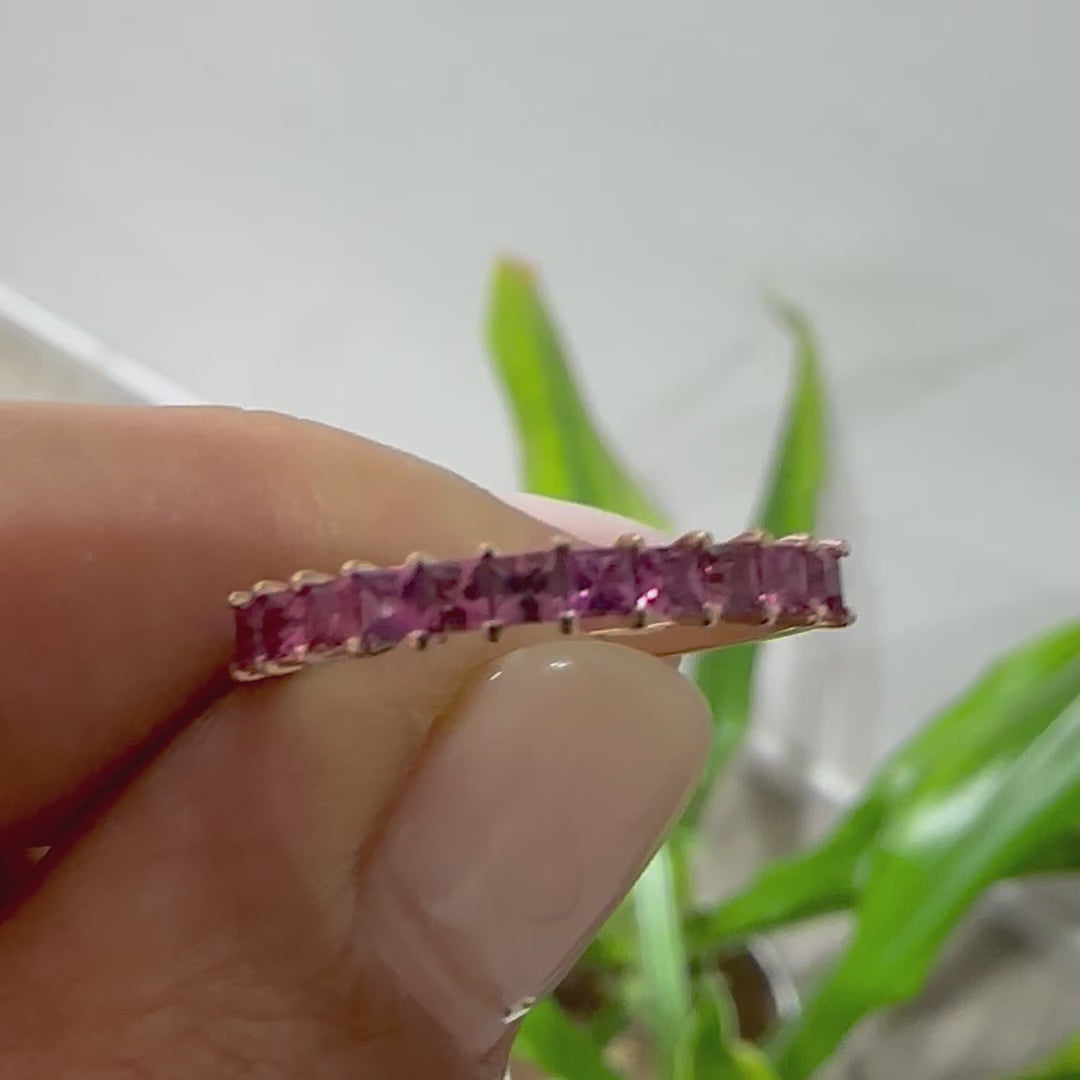 pink sapphires princess cut eternity displayed in person's hand