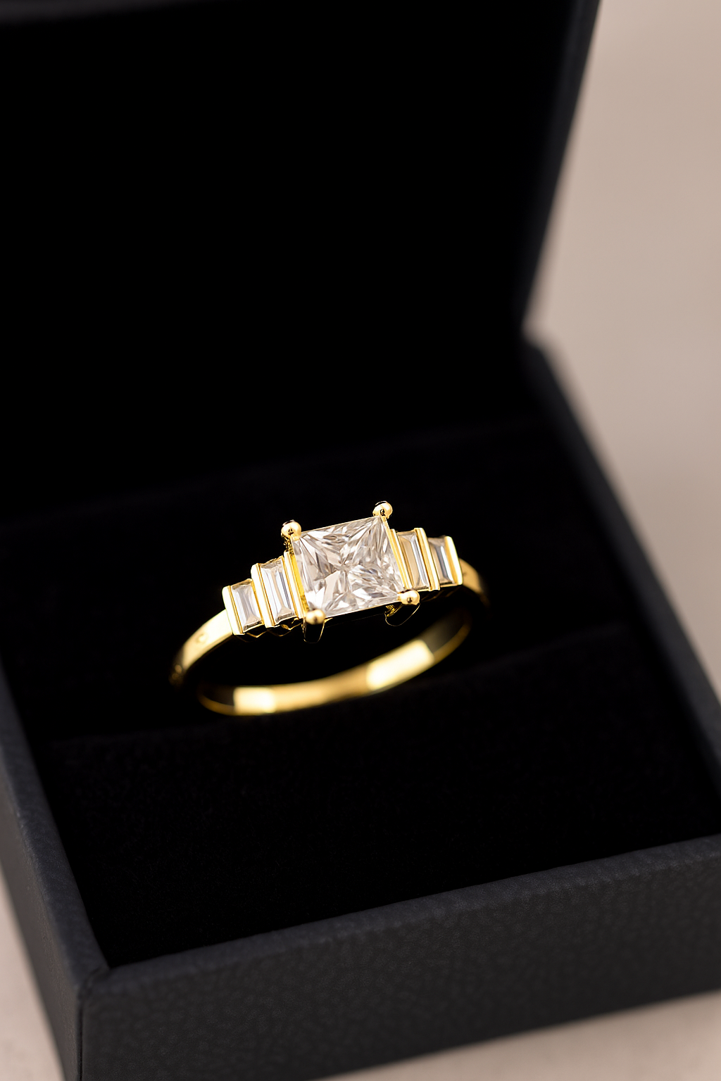 Princess and baguette five-stone engagement ring in yellow gold in a black jewelry box