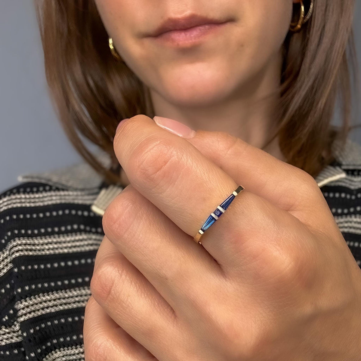 Blue sapphire three-stone ring in yellow gold worn on the hand