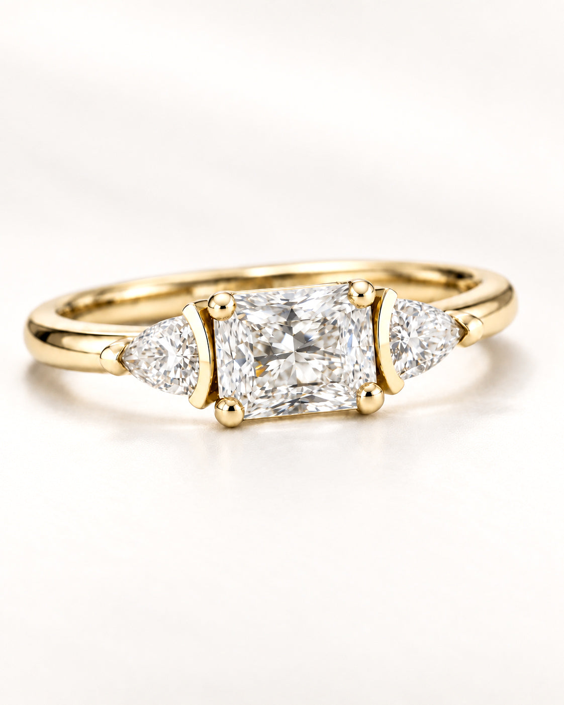 Three-stone engagement ring with a radiant-cut center diamond and trillion-cut side diamonds in yellow gold