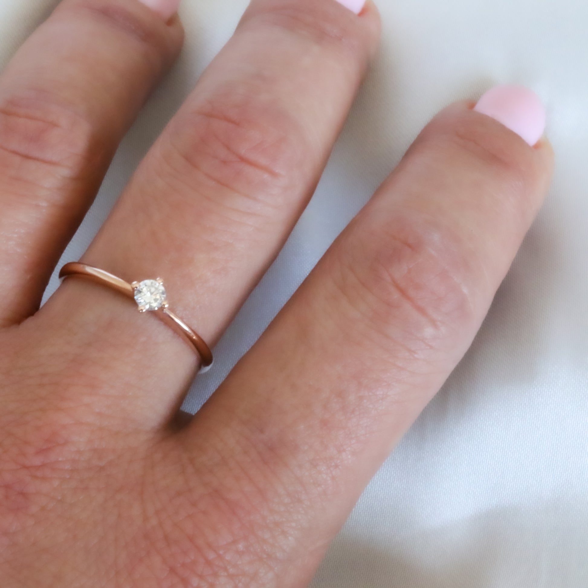 dainty rose gold solitaire diamond ring on finger 