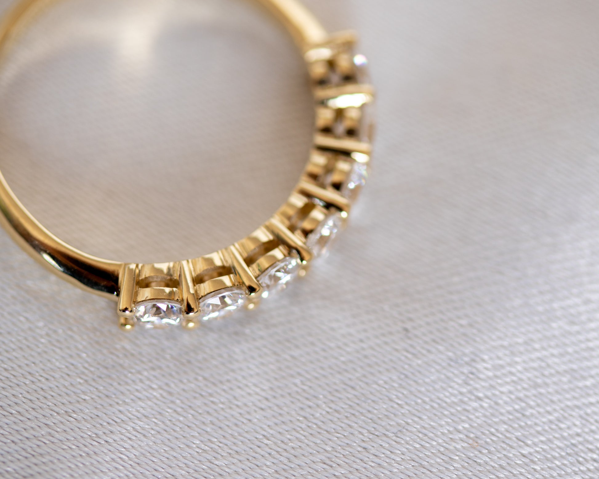 Round diamond half eternity band, angled view showing shared-prong setting