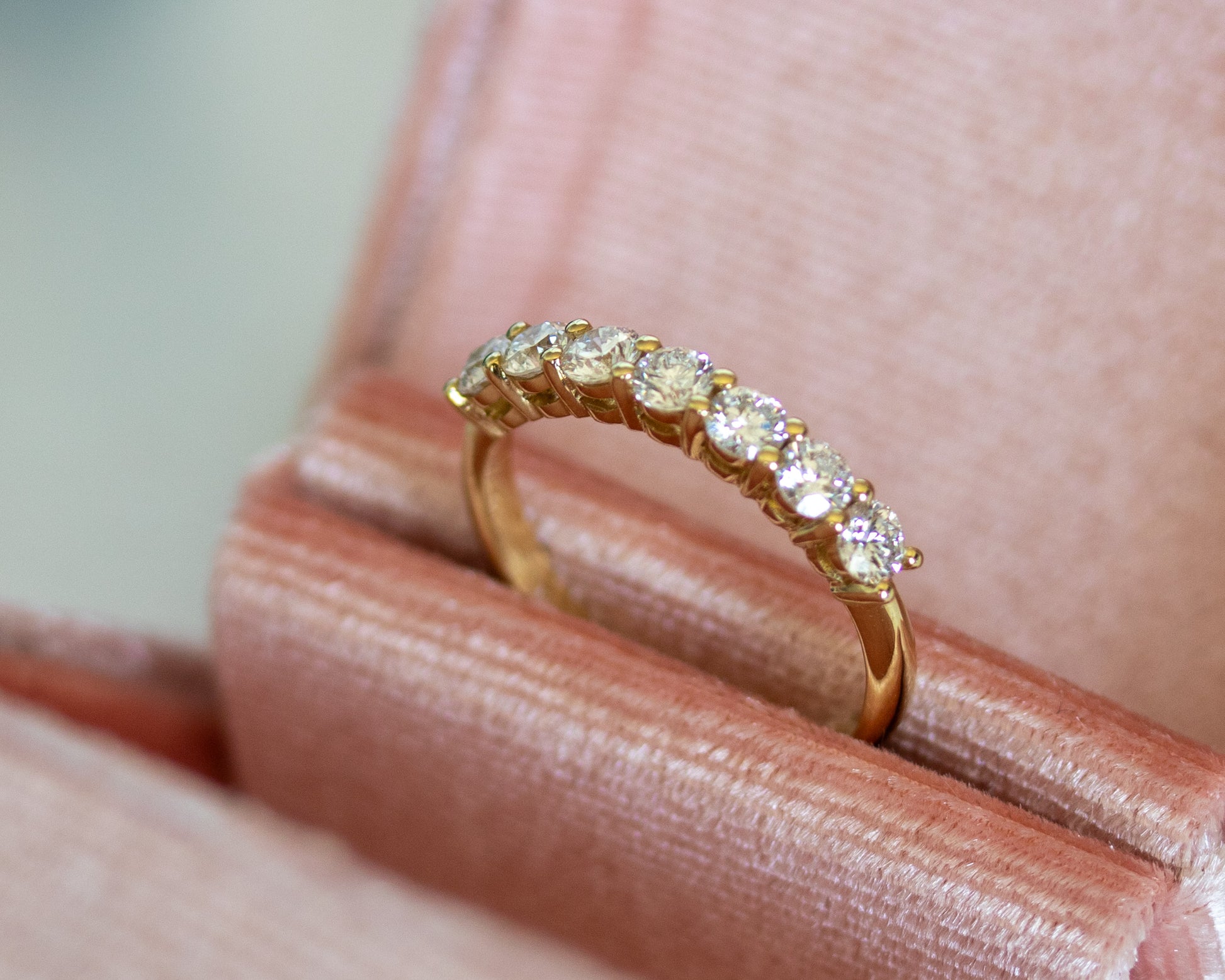 Gold round diamond eternity ring displayed in a blush jewelry box