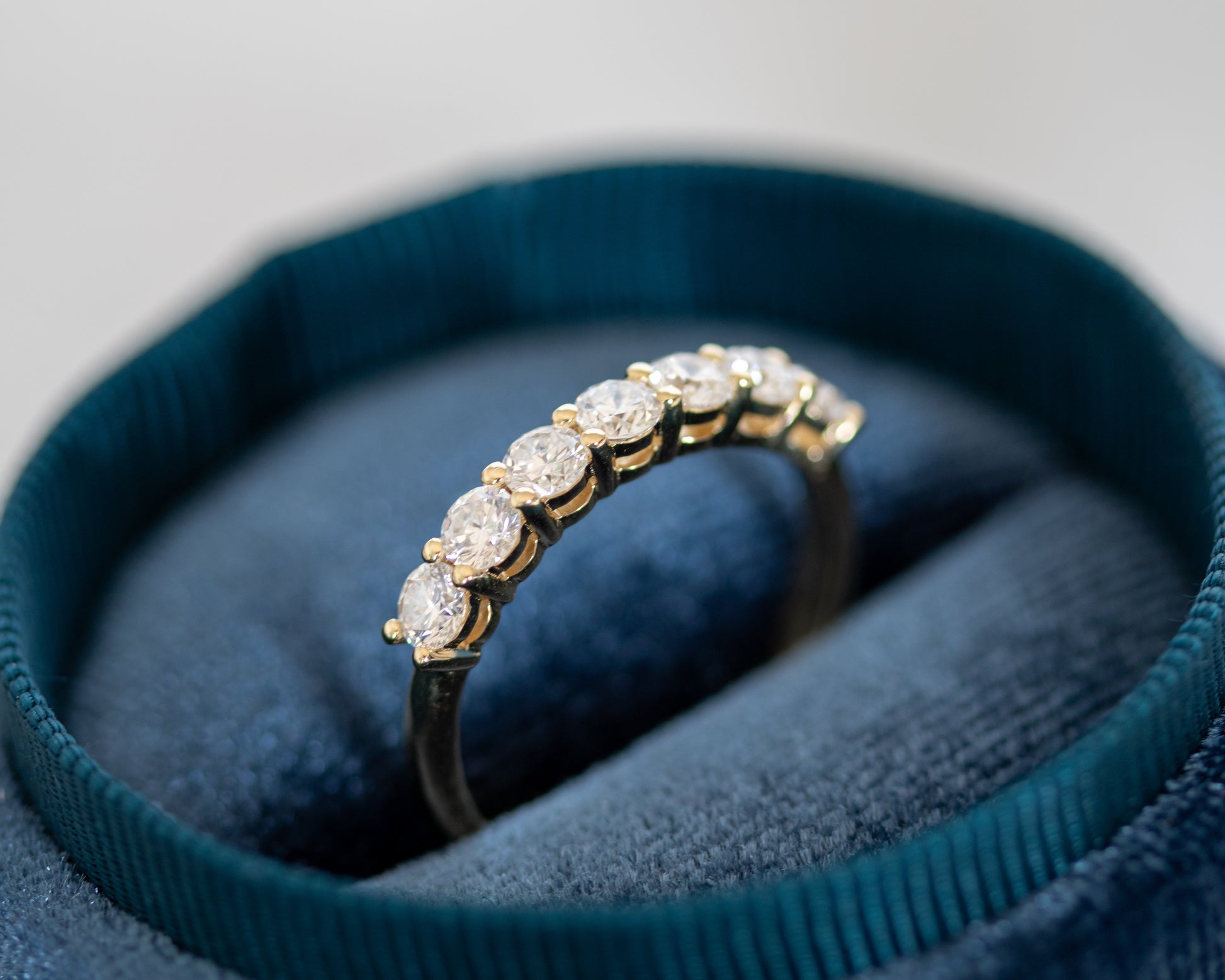 Gold round diamond eternity ring displayed in a teal jewelry box