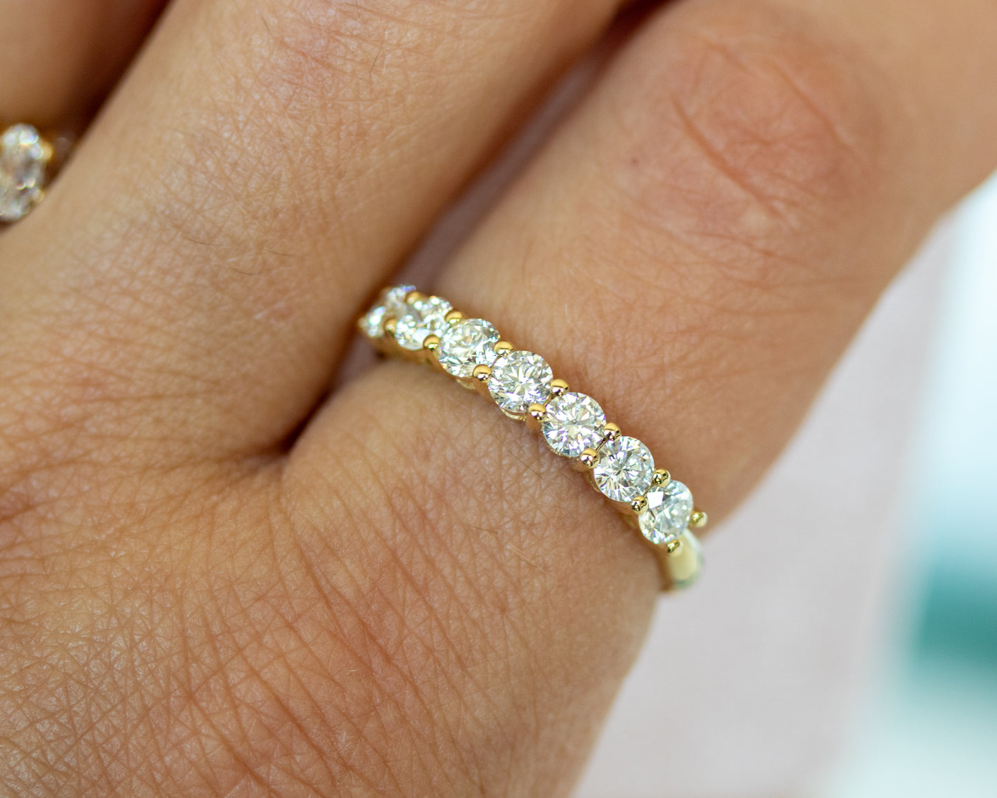 Round diamond half eternity ring worn on finger