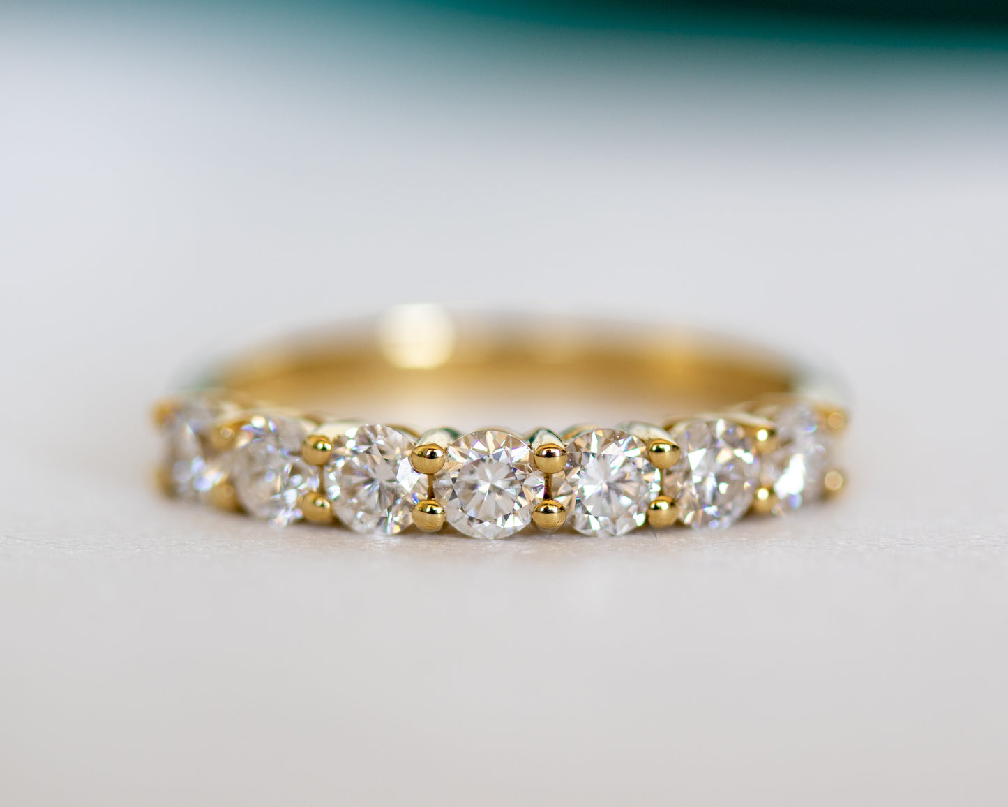 Round diamond half eternity ring in gold, close-up on textured surface