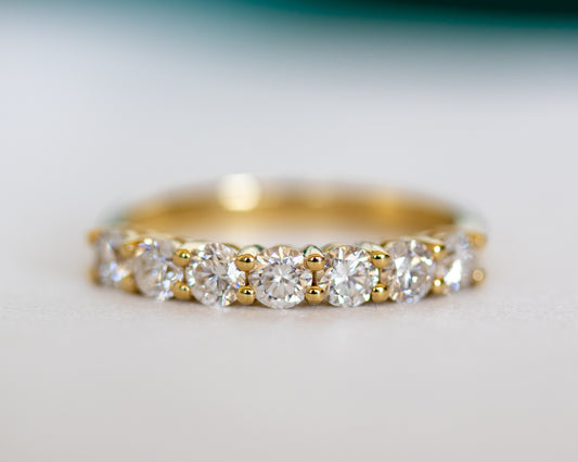 Round diamond half eternity ring in gold, close-up on textured surface