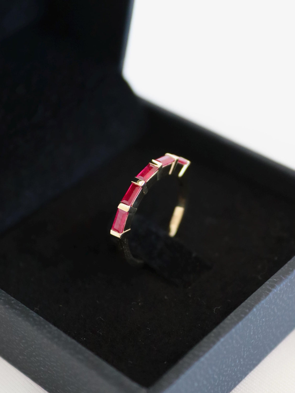 Five natural ruby baguettes bar-set east-west in a 14K gold ring in a black ring box
