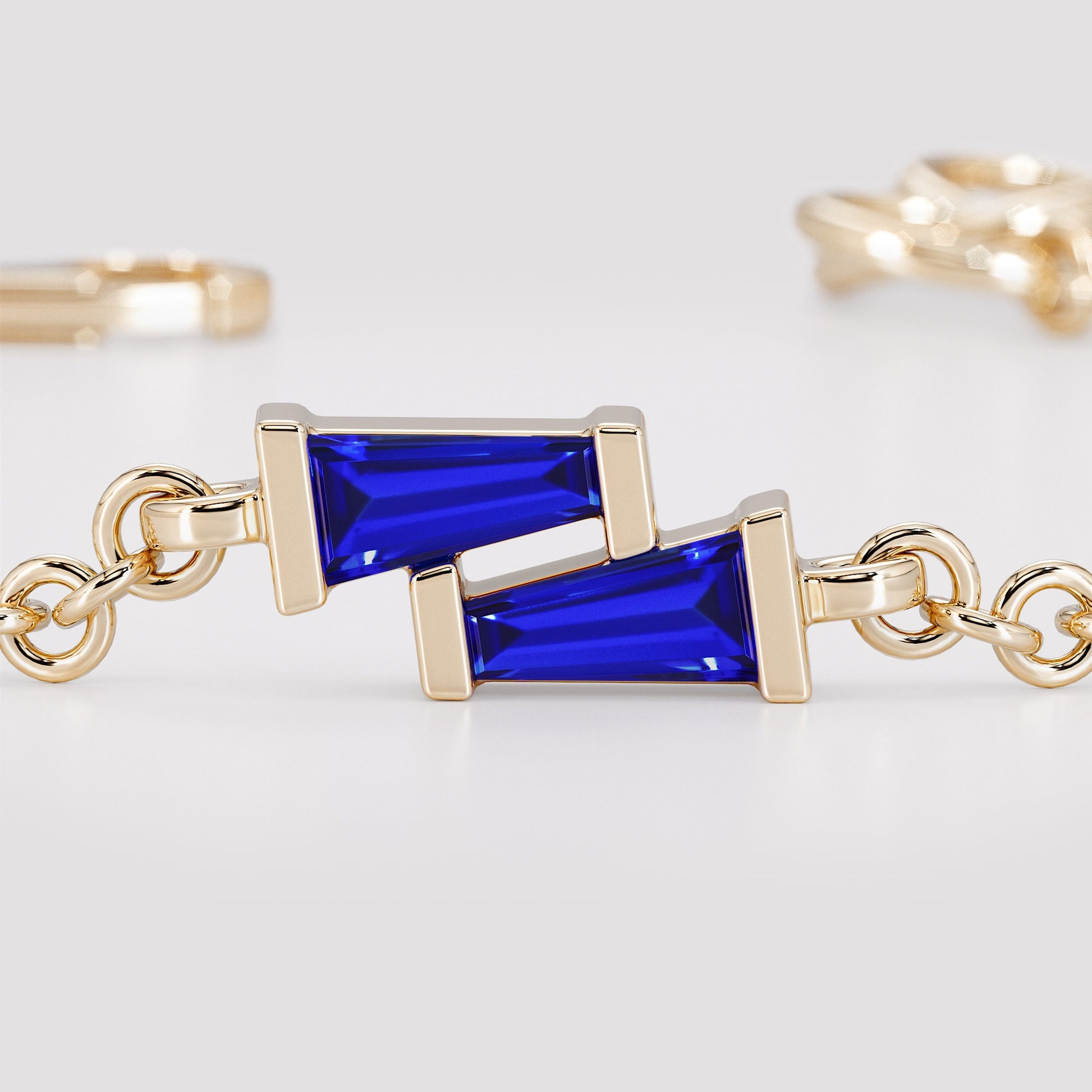 Close-up of two blue tapered baguette sapphires set in a gold bracelet charm
