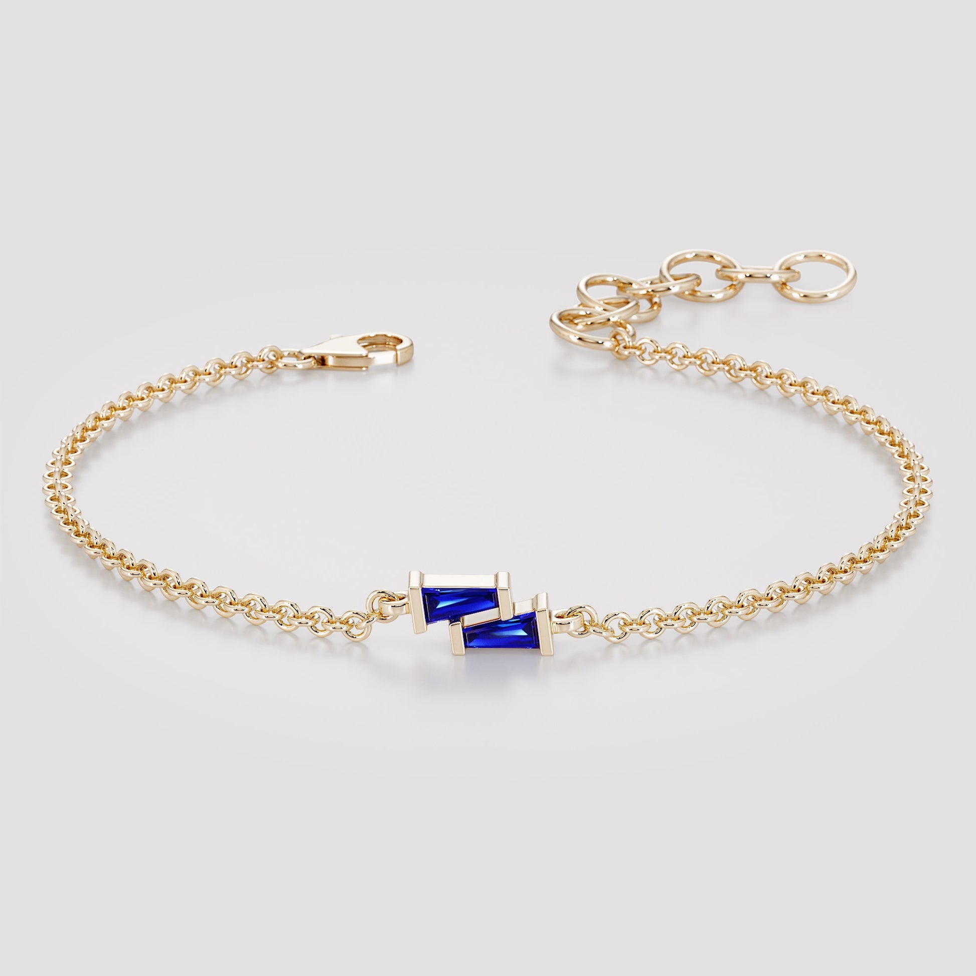 Gold chain bracelet with two blue tapered baguette sapphires and a lobster clasp