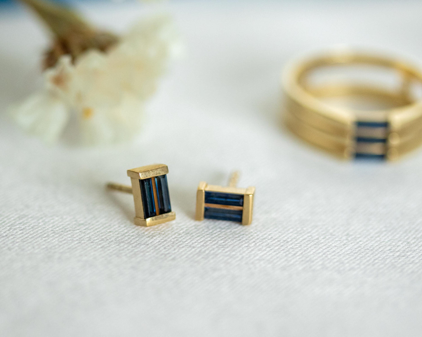 Blue sapphire baguette studs styled beside a matching gold sapphire ring