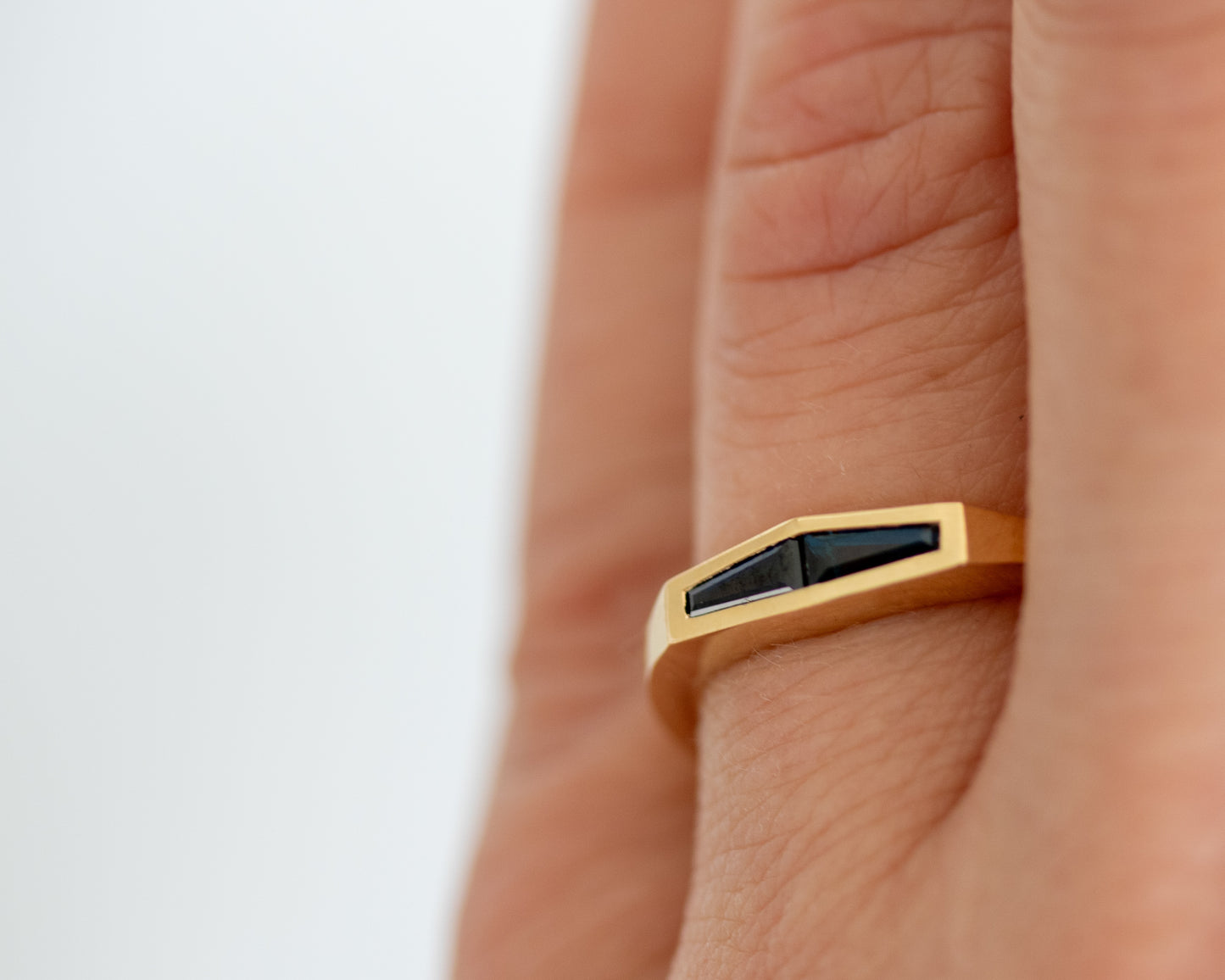 Two-stone tapered baguette blue sapphire ring in 14K yellow gold, worn on the hand in an overhead view.
