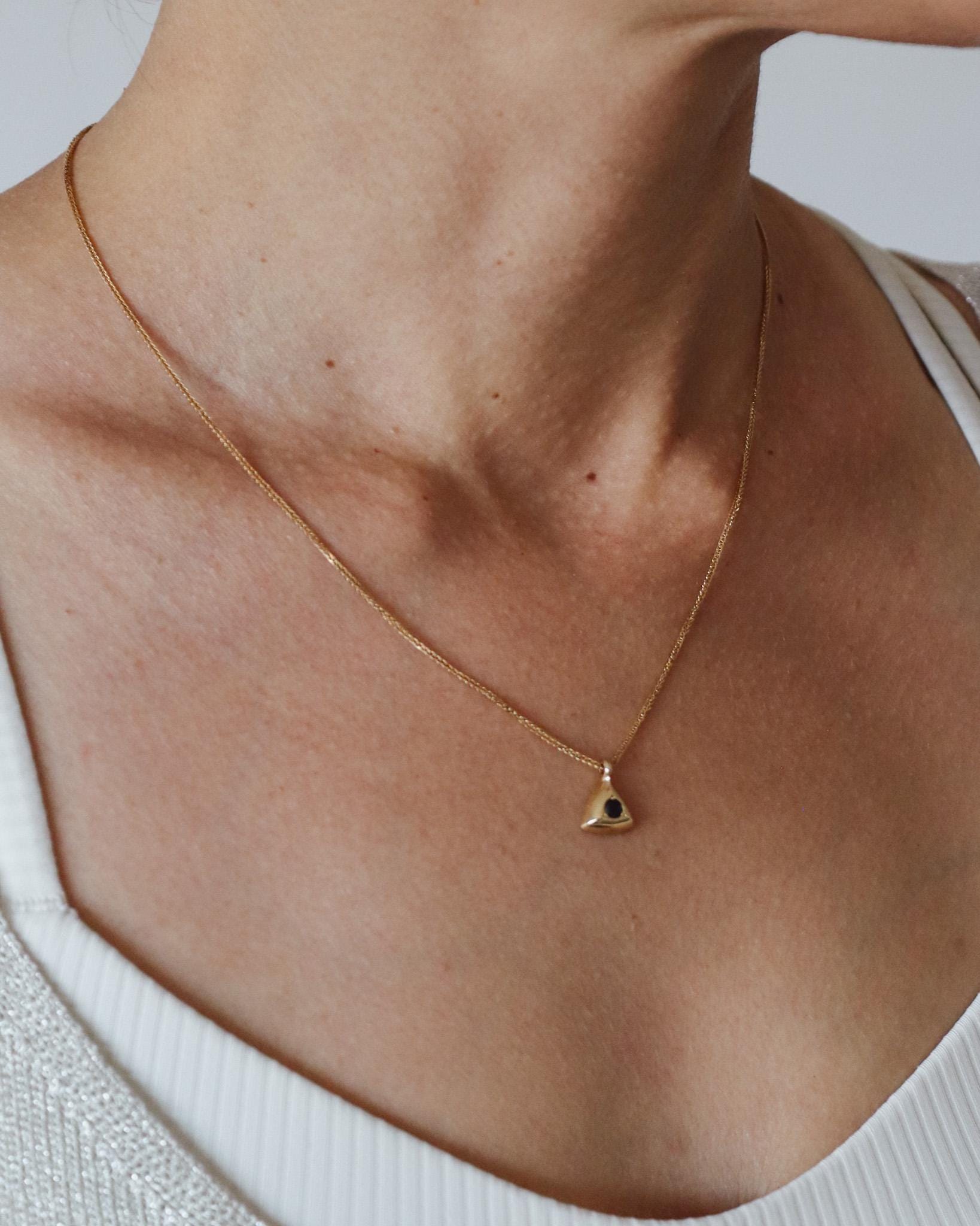 Blue sapphire triangle pendant necklace worn at the neckline