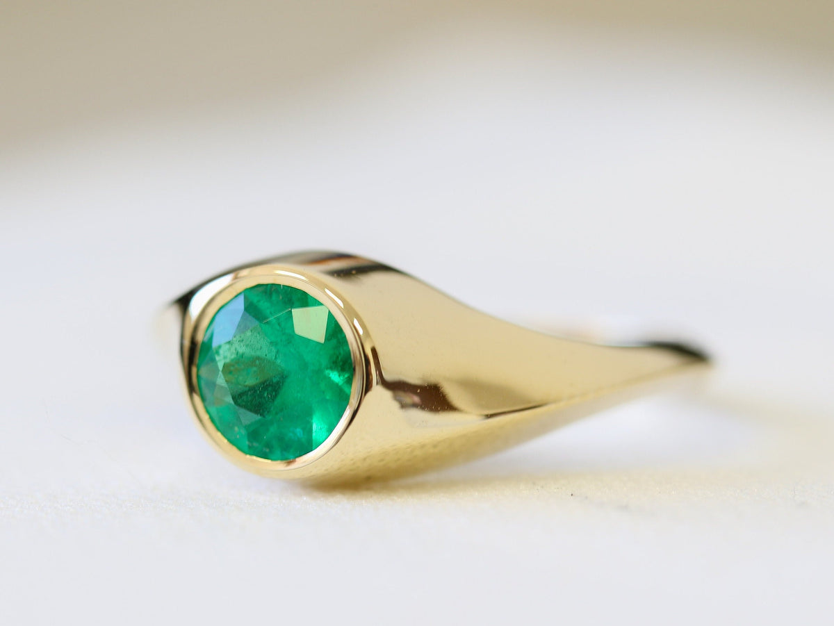 Bezel-set natural emerald in a sculptural yellow gold ring, three-quarter view