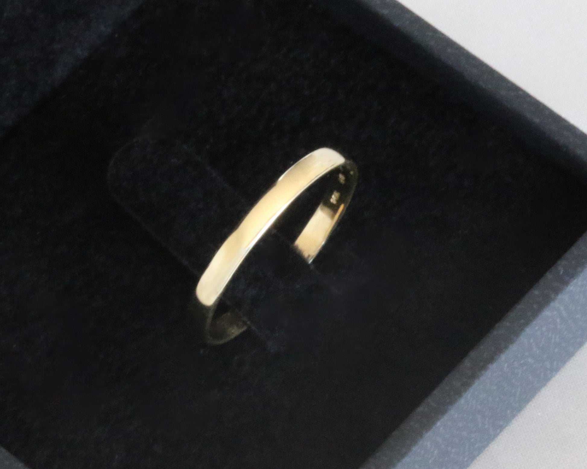 Gold ring on a black cushion in a jewelry box